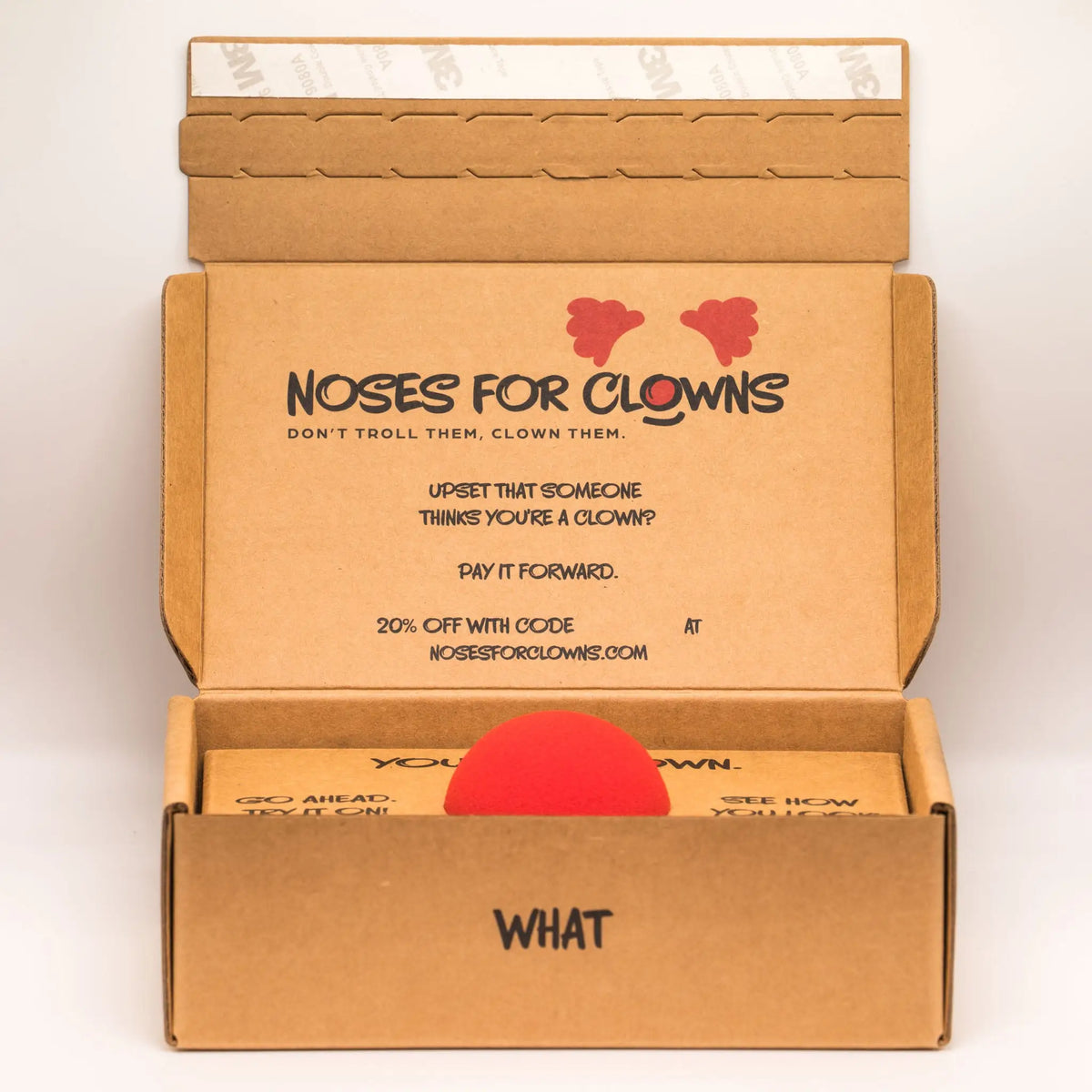 Open cardboard box with 'Noses for Clowns' branding and a red nose inside.