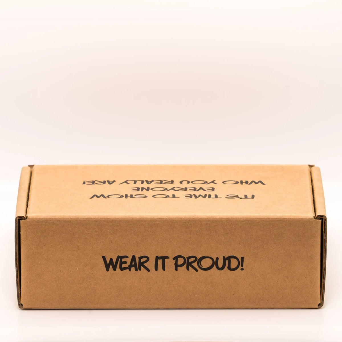 Cardboard box with 'Wear it proud!' text on the rear, on a white background.