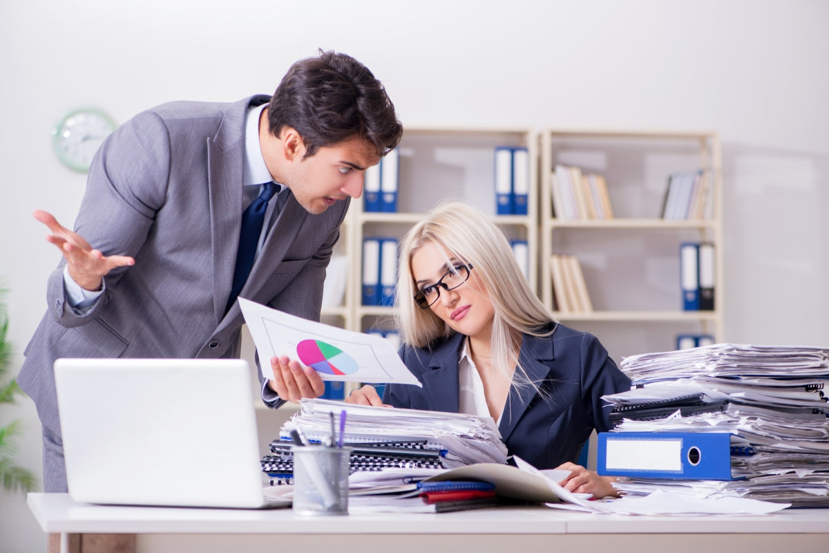 Clown boss rants over pie chart as stressed employee drowns in paperwork avalanche—office circus in full swing!