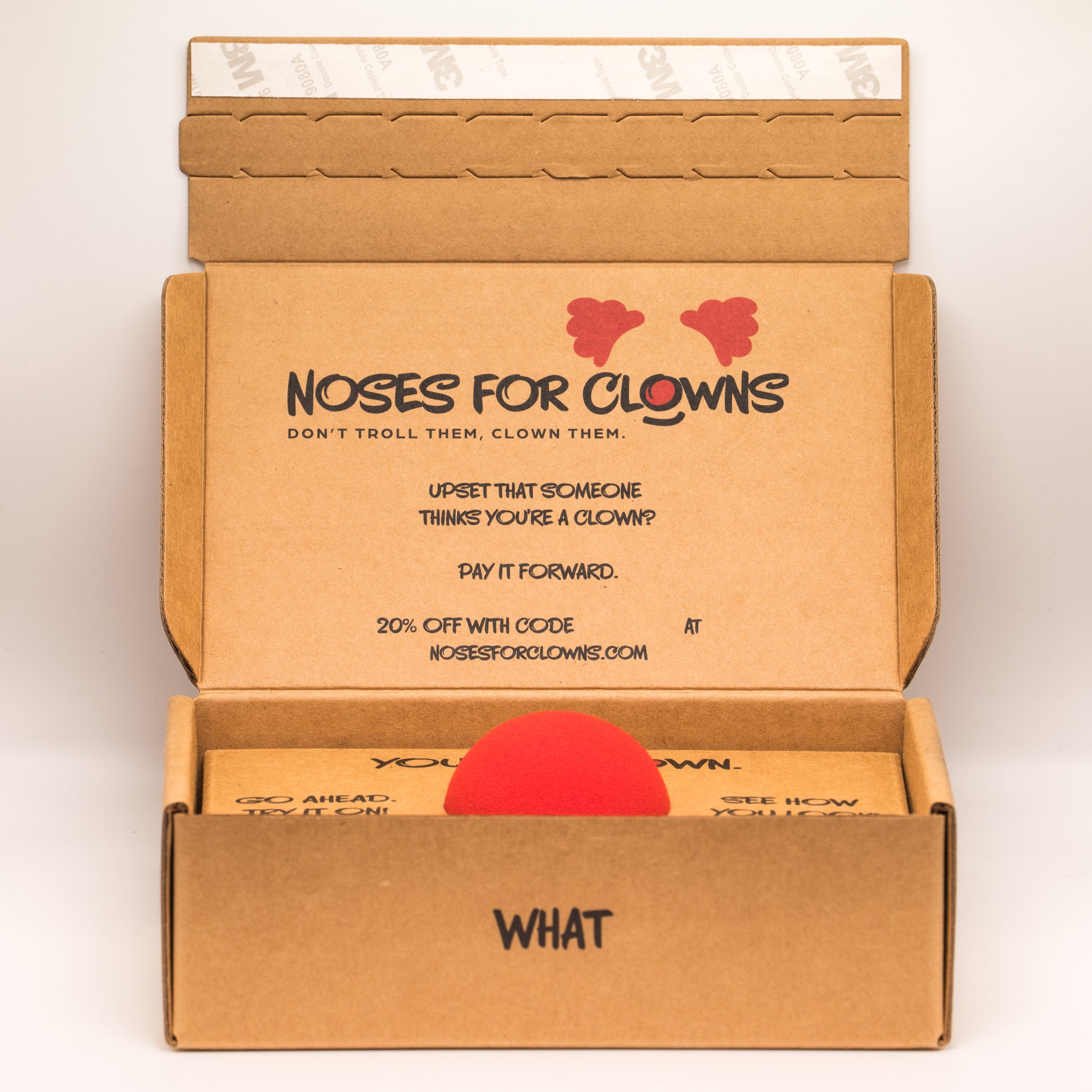 Open cardboard box with 'Noses for Clowns' branding and a red nose inside.