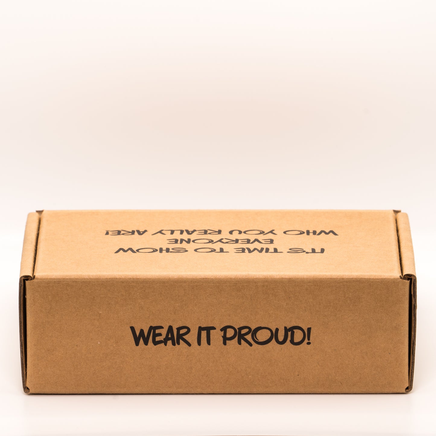 Cardboard box with 'Wear it proud!' text on the rear, on a white background.