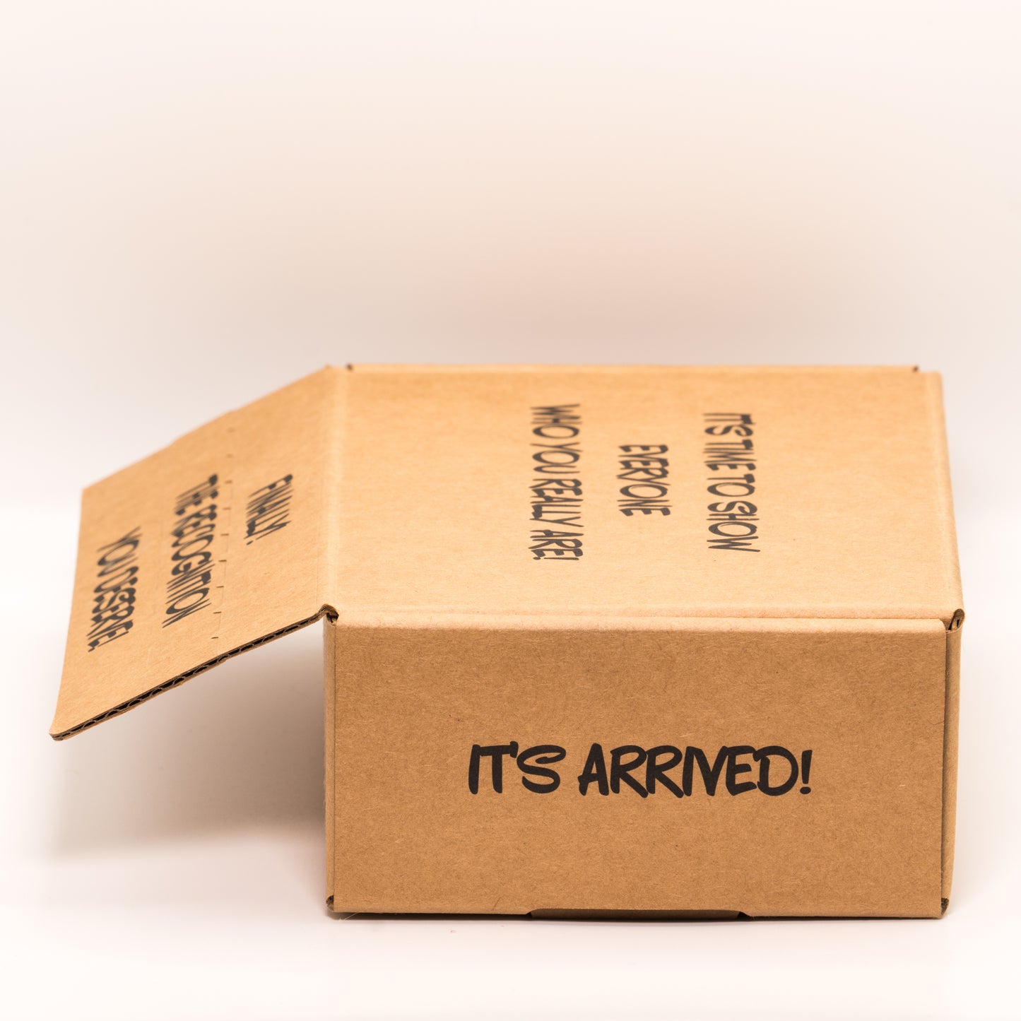 Open cardboard box with 'It’s Arrived!' text on right side on a white background.