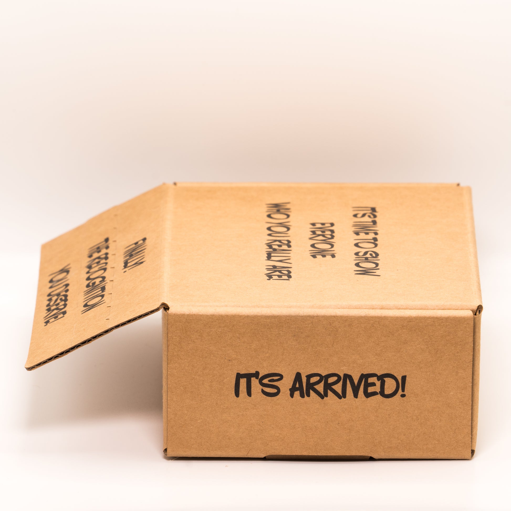 Open cardboard box with 'It’s Arrived!' text on right side on a white background.