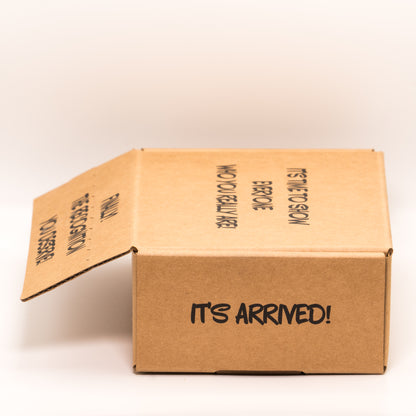 Open cardboard box with 'It’s Arrived!' text on right side on a white background.